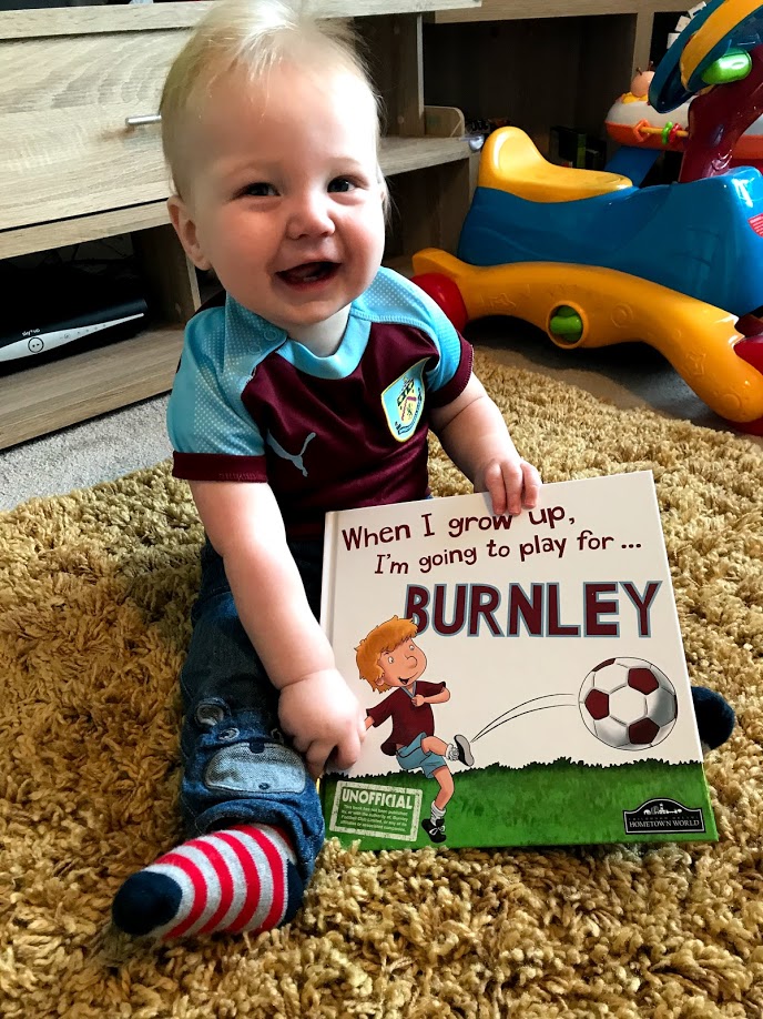 Noah in his Burnley FC shirt with his Burnley book.